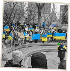 Marchers carrying Ukrainian flags and placards through a city street.
